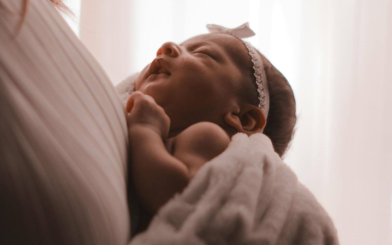 طفل حديث الولادة يستريح بين ذراعي أمه - اللحظات الأولى من الحياة والرعاية